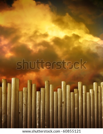 A wooden fence is in the foreground and red, gold and brown storm clouds are in the background. Use it to symbolize protection or a barrier concept.