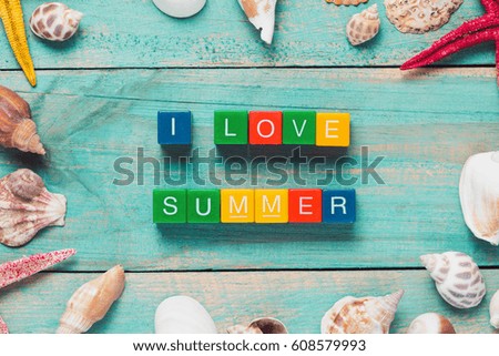 I LOVE SUMMER written in colorful wooden blocks on a wooden background with a starfish