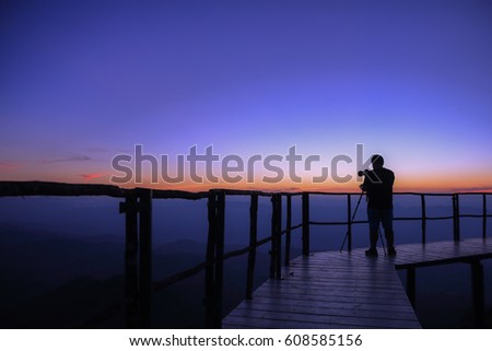silhouette of photographer on top of mountain at sunset background / selective focus 