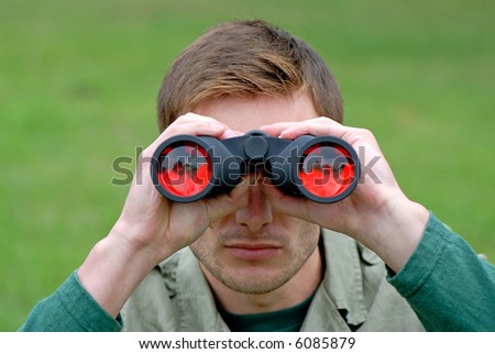 guy looks in the field-glass on  green background in park