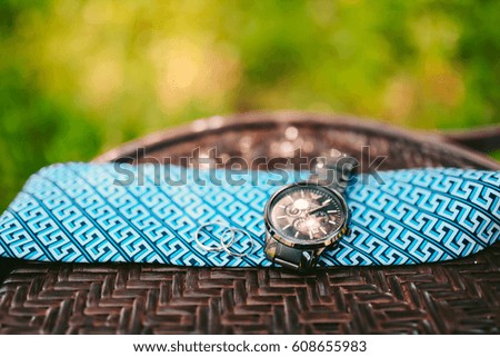 Watch the bride and rings lie on a blue tie. Photo Camping on a wooden background.