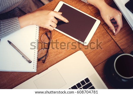 Technology concept: girl using a tablet with blank screen for copy space , hardwood desktop and stationery on background. Anonymous face