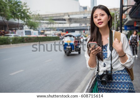 Woman walking in bangkok city using phone app for taxi ride hailing service or reading travel guide. Asian girl tourist searching for map directions on smartphone. Copy space.