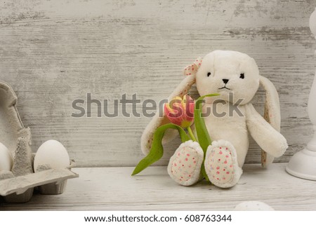 Bunny toy with tulips over wooden background. Easter day photo.