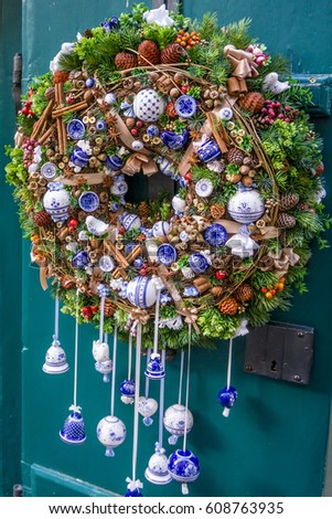 Christmas wreath with ceramic globes, bells, cones and evergreen boughs on a blue door