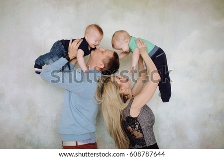 Father and mother playing with two little sons.Two little kid boys, siblings twins and parents having fun. Happy father, mother and two children playing together.