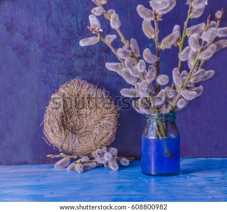 Easter still life of fur seals willow branches and nest on blue wooden background
