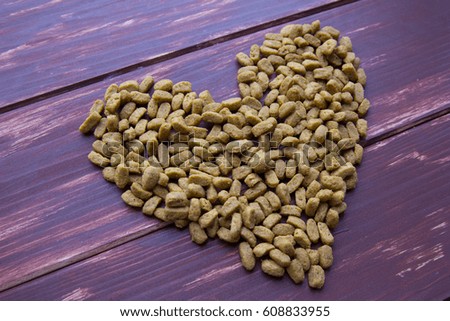 Heart made of dog feed at old brown wood background