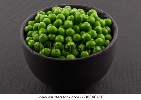 Bowl of green wet pea isolated on dark stone background