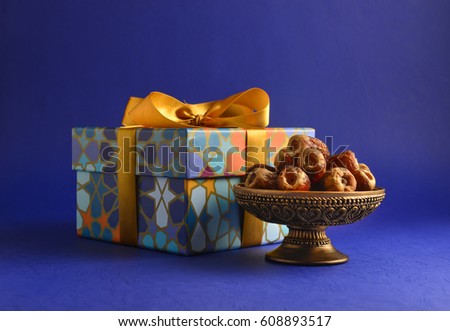Decorative gift box with golden ribbon and dates. Islamic festive gift and dates. Stock photo. 