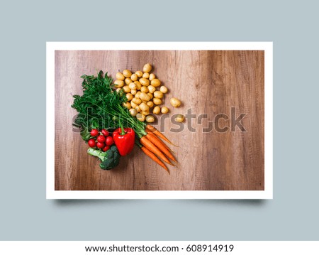 Potatoes with carrot and pepper. Red radish, broccoli and raw new potato. Fresh natural vegetables. Organic bio food. On wooden table. Photo frame design with shadow.
