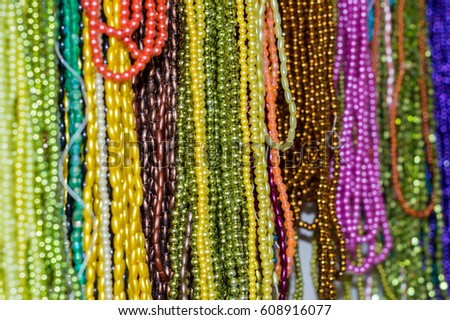 Strings of colorful beads hung at outdoor crafts market for sale