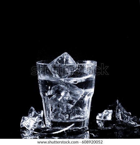 A glass with clear water and ice on a black background