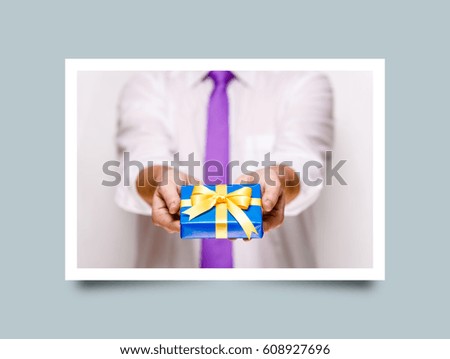 Male hands holding a gift box. Present wrapped with ribbon and bow. Christmas or birthday blue package. Man in white shirt and necktie. Photo frame design with shadow.