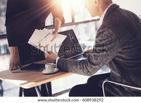 Two partners making research for new business direction.Adult businessman working modern laptop and showing documents to young colleague.Business people meeting concept.Visual effects,blurred