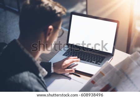 Closeup view of banking finance analyst in eyeglasses working at sunny office on laptop while sitting at wooden table.Businessman analyze stock report on notebook screen.Blurred,horizontal mockup