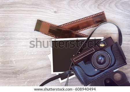 Old retro camera, photos and film on a wooden background.
