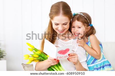 Happy mother's day! Child daughter congratulates moms and gives her a postcard and flowers tulips
