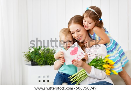 Happy mother's day! Children congratulates moms and gives her a postcard and flowers tulips
