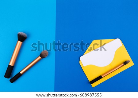 Beauty background. Make up brushes with yellow envelope and blank card Top view. Flat lay.