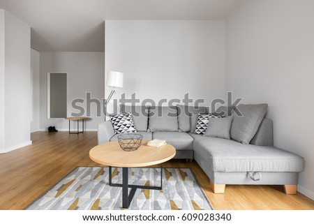 Modern living room with grey sofa with decorative pillows and small round table