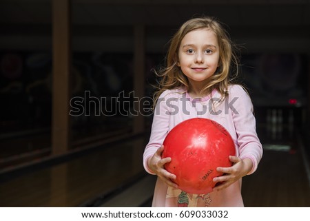 beautiful little girl in the bowling and keeps the ball in his hands