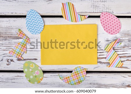 Blank card and Easter cutouts. Colorful paper crafts on wood.