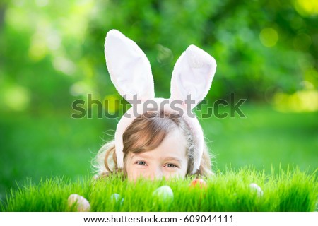 Happy Easter bunny. Child having fun outdoor. Kid playing with eggs on green grass. Spring holidays concept