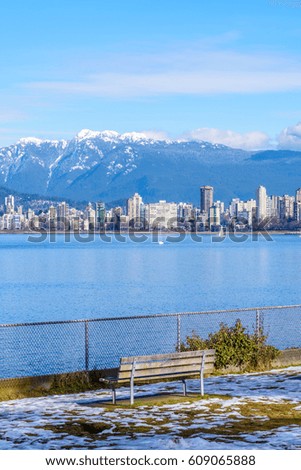 View on Vancouver Downtown and Mountains over ocean and a park bench on the foreground. British Columbia. Canada.