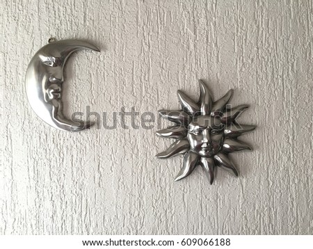 Moon and sun decorations in silver hanging on a white wall