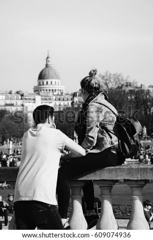 Luxembourg gardens in Paris (France). Couple relaxing on balustrade with the view on Pantheon. Unrecognizable people. Black and white.