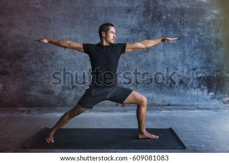 Man practicing advanced yoga against a dark wall