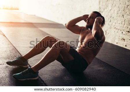 Muscular man exercising doing sit up exercise. Athlete with six pack, white male, no shirt Royalty-Free Stock Photo #609082940