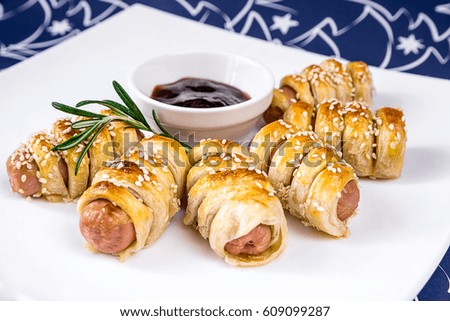 Homemade sausage rolls with sauce on a white plate. Delicious food for parties.