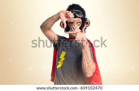 Superhero monkey man focusing with his fingers on ocher background