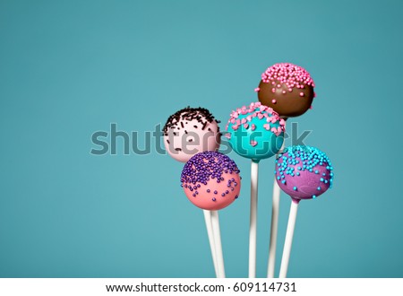 Assorted cake pops with sprinkles over a teal blue background. Royalty-Free Stock Photo #609114731