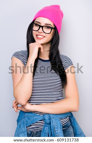 Portrait of stylish smiling pretty woman in pink hat and spectacles touching her chin with hand.