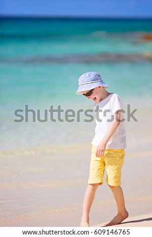 caucasian little boy being playful at picture perfect beach enjoying summer vacation