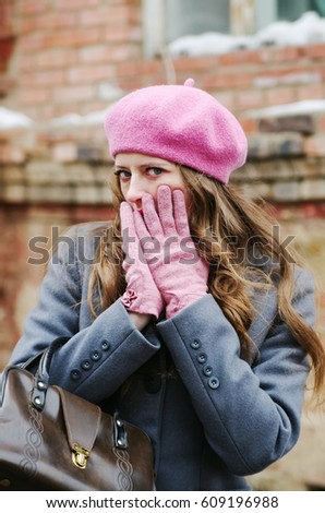 Girl in a gray coat and a pink beret, covers her face with her hands / The picture was taken in Russia, in the city of Orenburg, on Kobozev Street.