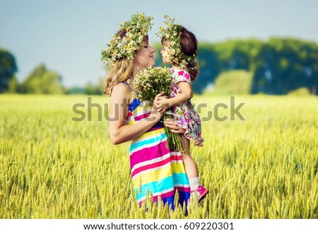 girl and mother in wheat field with bunch of daisies. selective focus. 