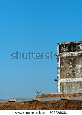 old aged dirty facade of an old residential or warehouse building in country composition with dry grass roof texture of a local shop, isolated with clear blue sky background as flexible copy space 