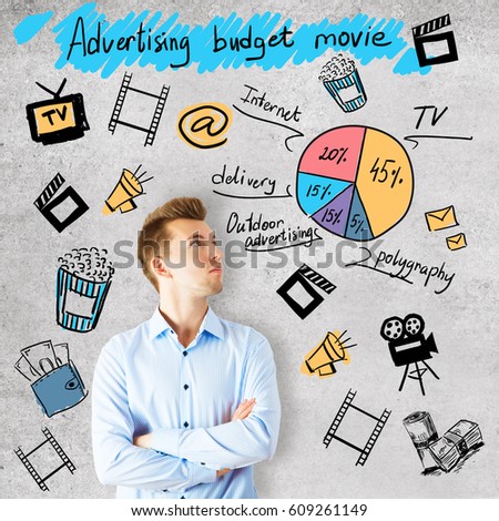 Attractive young man on concrete background with cinematography related drawings. Advertising budget movie concept