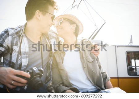 a nice tourist couple, while they are kissing sitting on a bridge with a beautiful sun light on the background