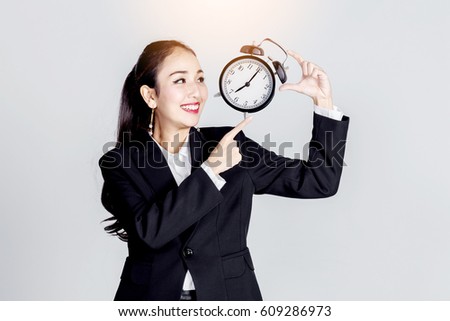asian business woman smile and point finget to black retro alarm clock isolate white background
