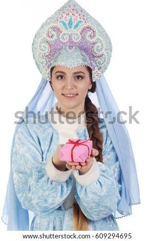 Portrait of a fairy-tale Snow Maiden in a blue suit and kokoshnik with a veil, gives a gift in a pink box
