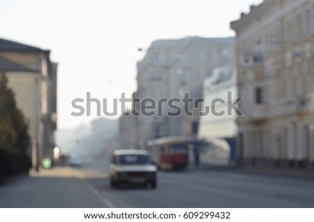 The blurred landscape of city streets with moving cars and tram during a foggy morning. Artistic reception of a blurred landscape photo with a bokeh effect