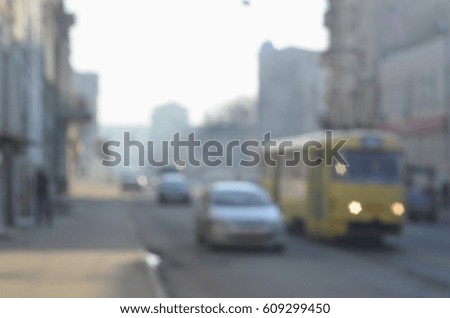 The blurred landscape of city streets with moving cars and tram during a foggy morning. Artistic reception of a blurred landscape photo with a bokeh effect
