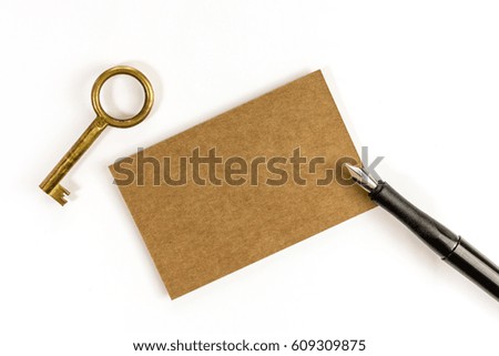 A photo of a kraft paper business card with an ink pen and a vintage key on a white background. A mockup or a minimalist banner with copy space