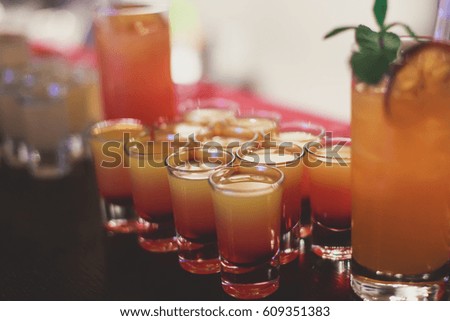 Beautiful row line of different colored alcohol cocktails with mint on a christmas party, martini, vodka,and others on decorated catering bouquet table on open air event, picture with beautiful bokeh