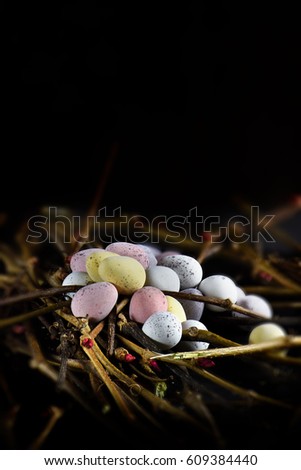 Rustic concept image for Easter celebrations. Candy eggs set against a dark natural background with creative lighting and selective focus with generous accommodation for copy space.